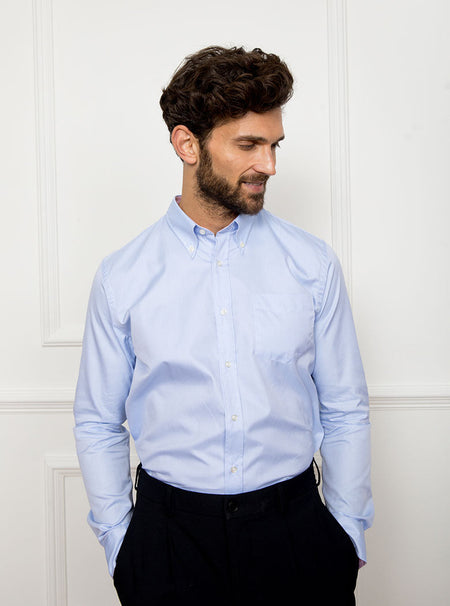 Man wearing a sky blue long sleeved shirt with a button down collar made with 100% Royal Oxford Cotton.